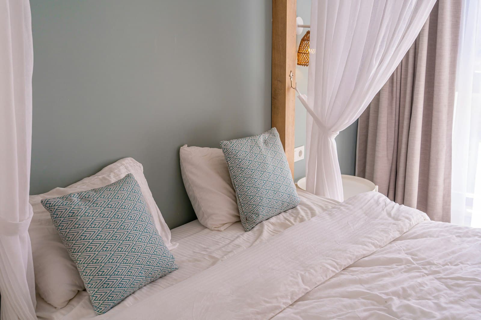 Almohadas de lino en una cama con dosel de algodón blanco