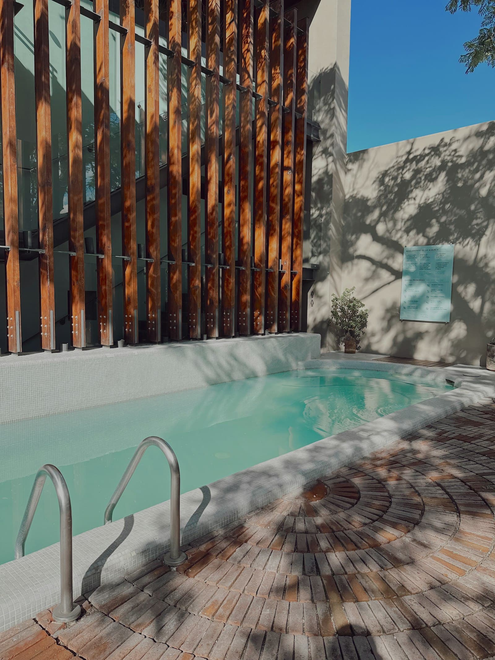 Piscina de inmersión en el patio del spa, a la sombra de una celosía de madera